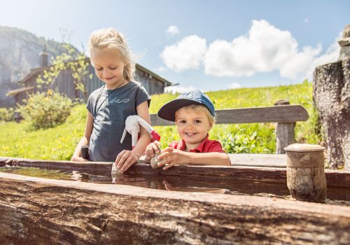 Kinder an einem hölzernen Wassertrog