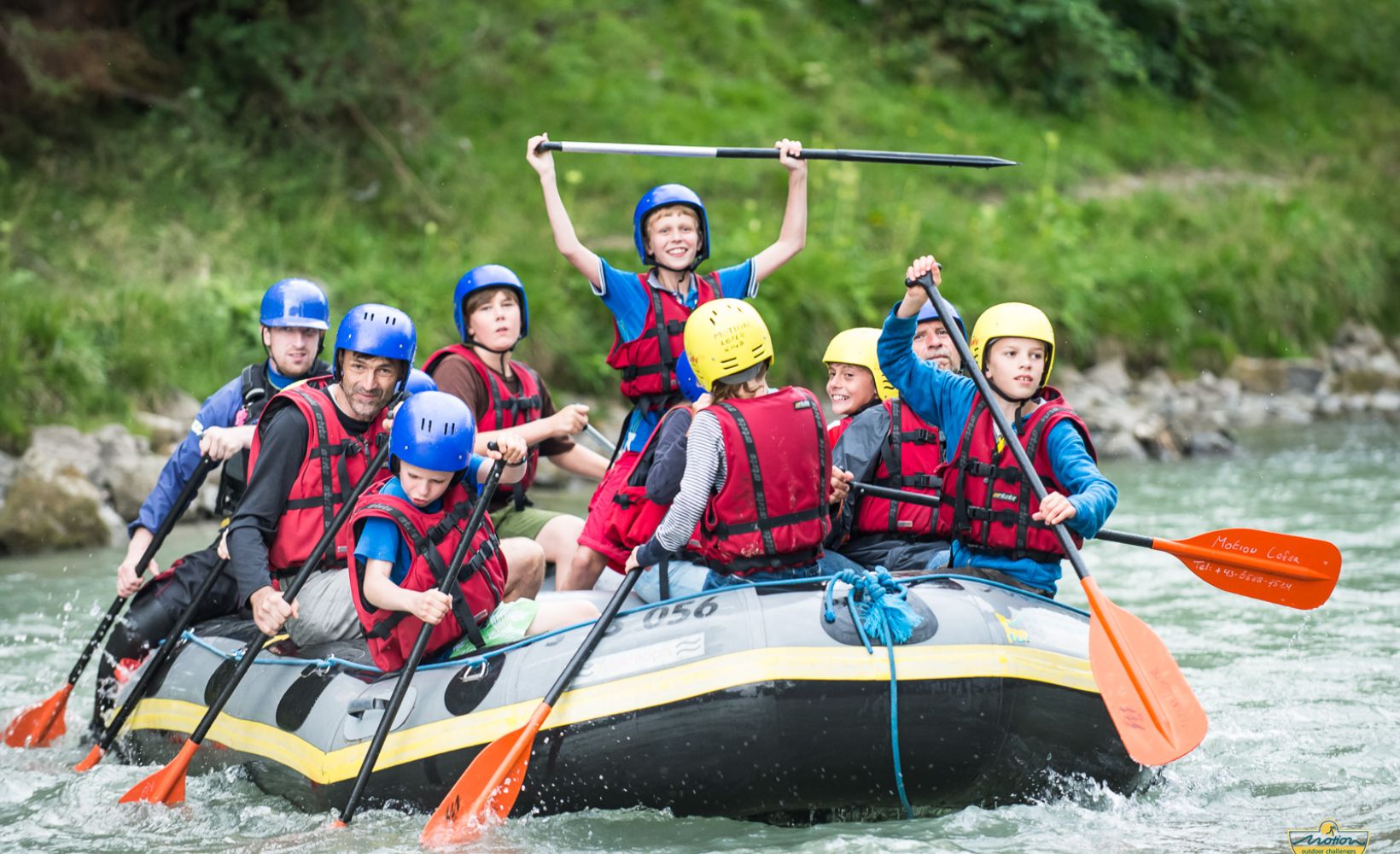 Familie mit Helmen und Schwimmwesten im Raftingboot